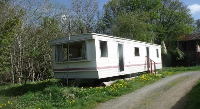caravan nestled away amongst trees on edge of farm yard, จอง พักในฟาร์ม Llandderfel กวินเนดด์